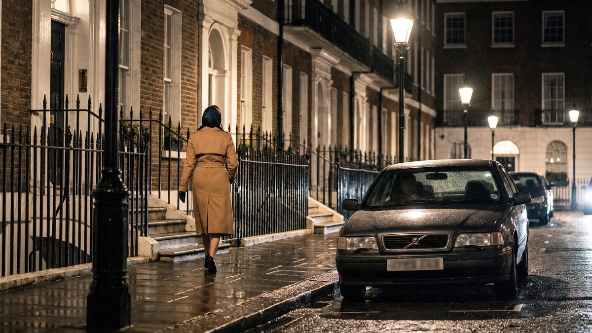 A woman in a trench coat on a London street at night